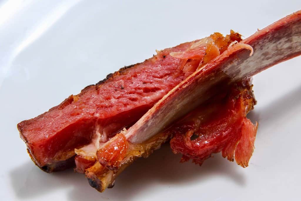 東洋肉店の骨付き羊のスモークベーコン、羊ベーコンの肉を皿の上でほぐす