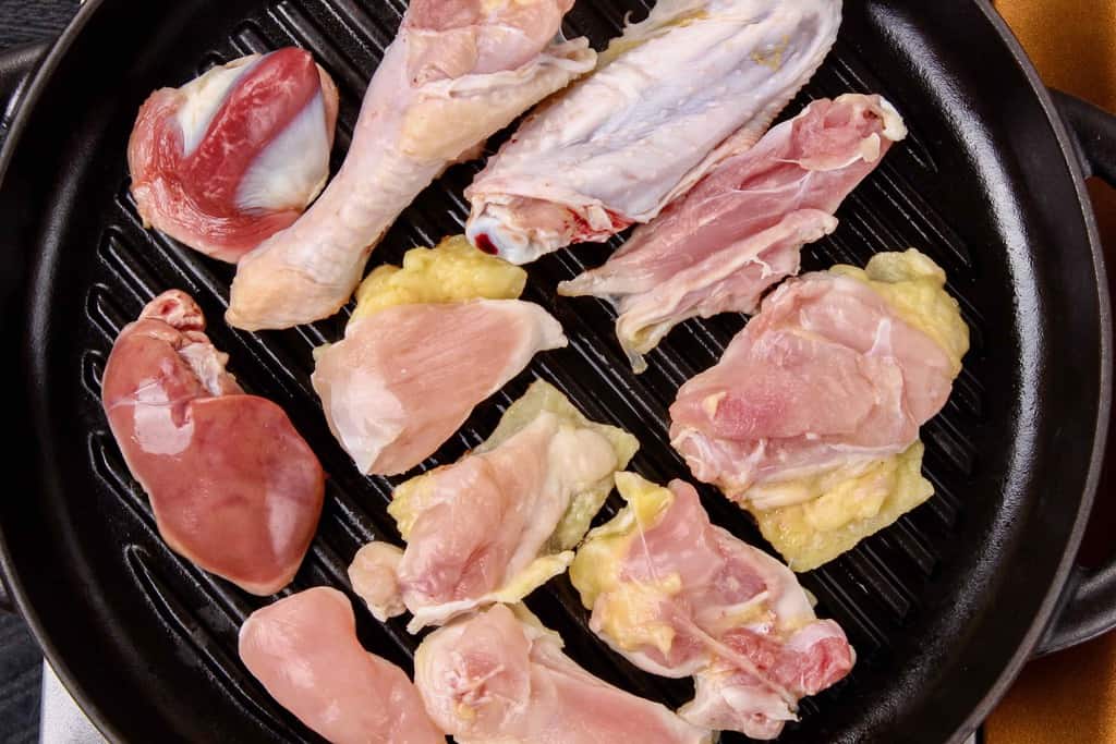 ストウブのグリルパンにさつま地鶏の生肉を並べる