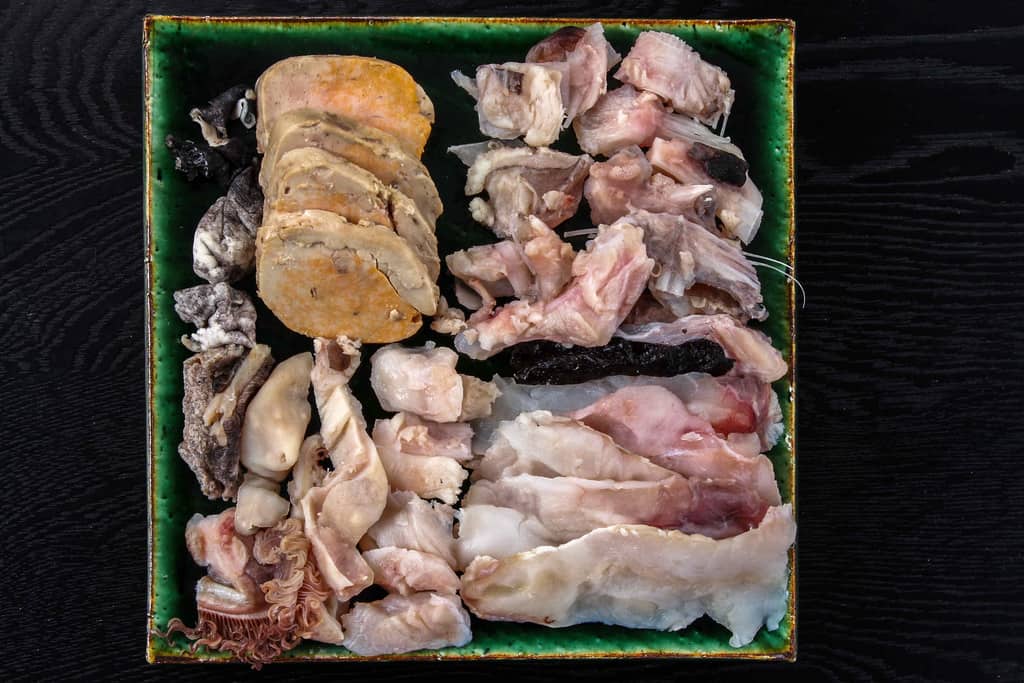 皿に盛り付けた鍋料理で使う鮟鱇の具材、あんこうの七つ道具（ヤナギ・皮・水袋・キモ・ヌノ・エラ・トモ）