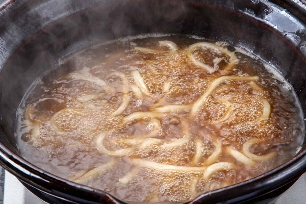 土鍋の中でアンコウ鍋の締めのうどんを煮込む