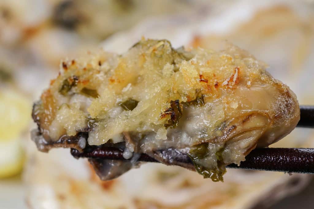 北海道厚岸産牡蠣のバターグリルを箸で持ち上げる