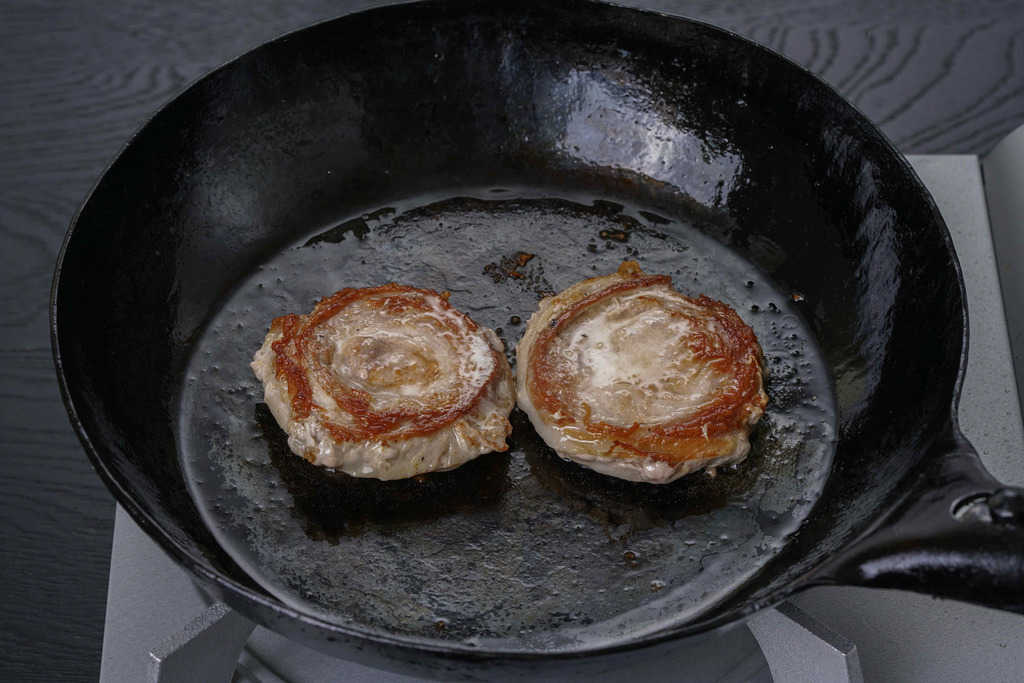 鉄フライパンの上でこんがりと焼きあがった2枚の黒豚ロールステーキ