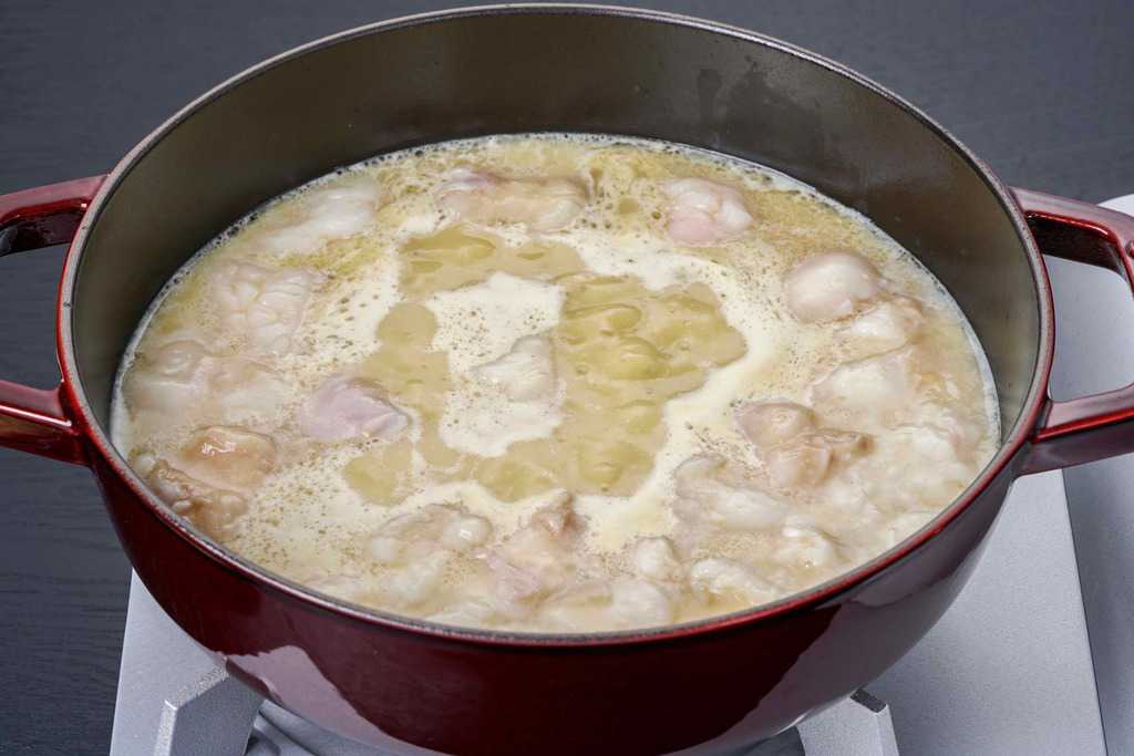 ストウブ鍋の中の煮立ったスープと牛モツ