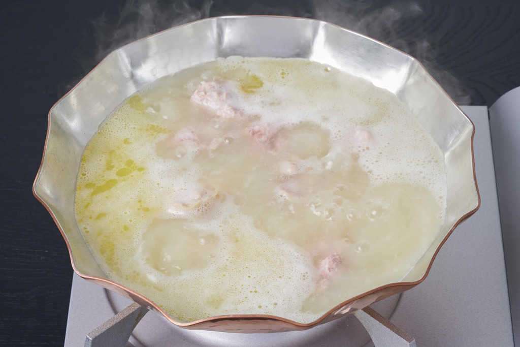 銅鍋の中の沸騰する水炊きスープ、博多とり田の水炊き鍋