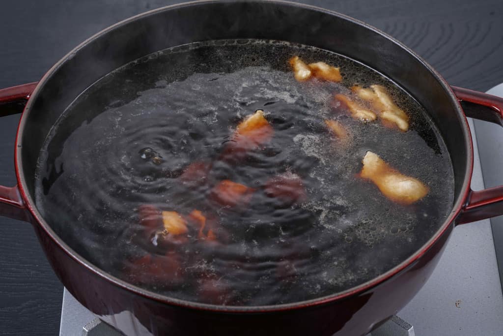ストウブ鍋の中のスープで煮込む鶏モモ肉