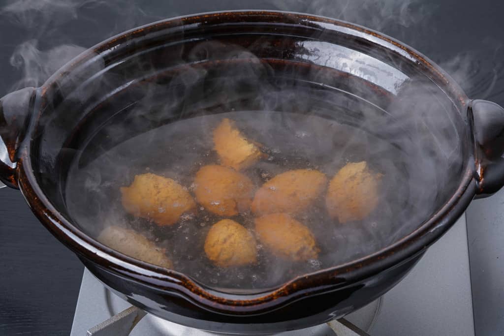 土鍋の中のスープで煮込むひと口大の合鴨ミンチ