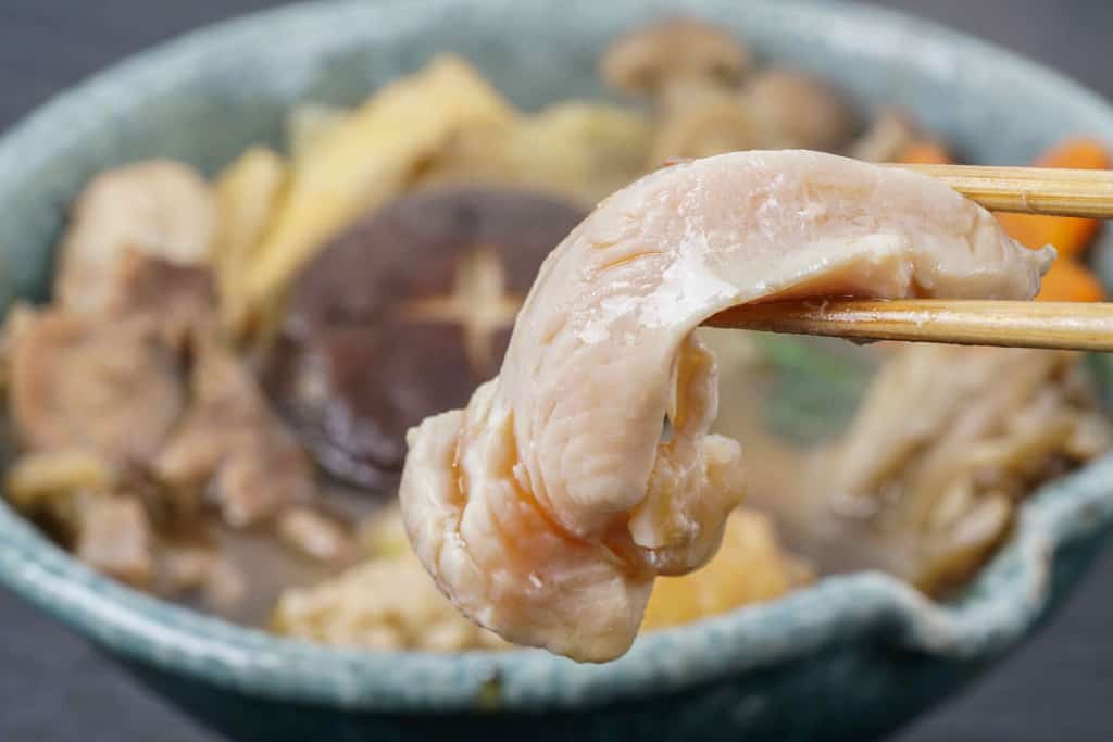 近江軍鶏鍋のムネ肉を箸で持つ
