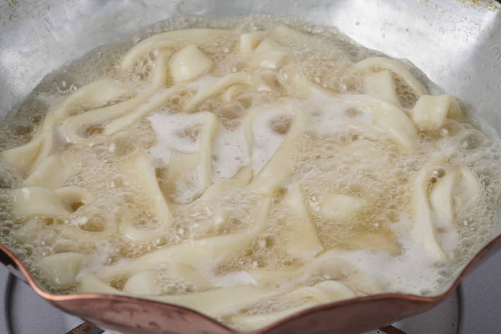銅鍋の中の名古屋コーチン水炊きスープできしめんを煮込む、水炊き鍋の〆のきしめん