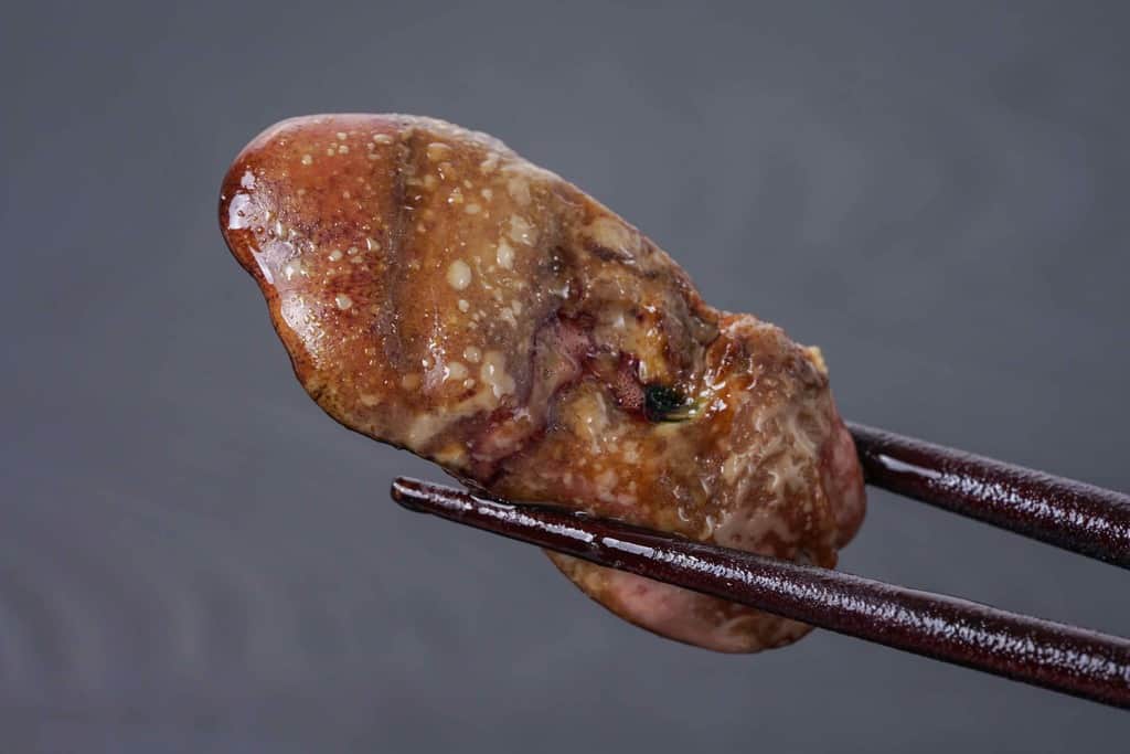 名古屋コーチンのレバー（肝臓）のグリルを箸でつまむ