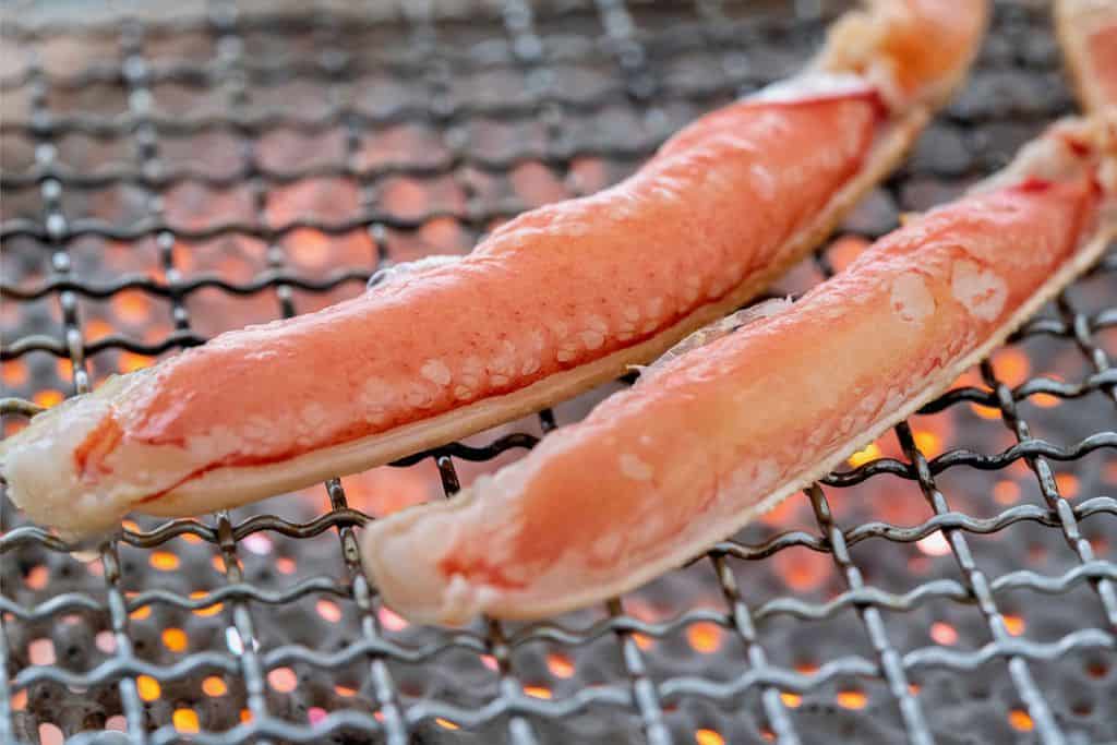 生のズワイガニの足肉を焼く、焼き網の上で越前かに職人甲羅組のカット生ずわい蟹を焼く