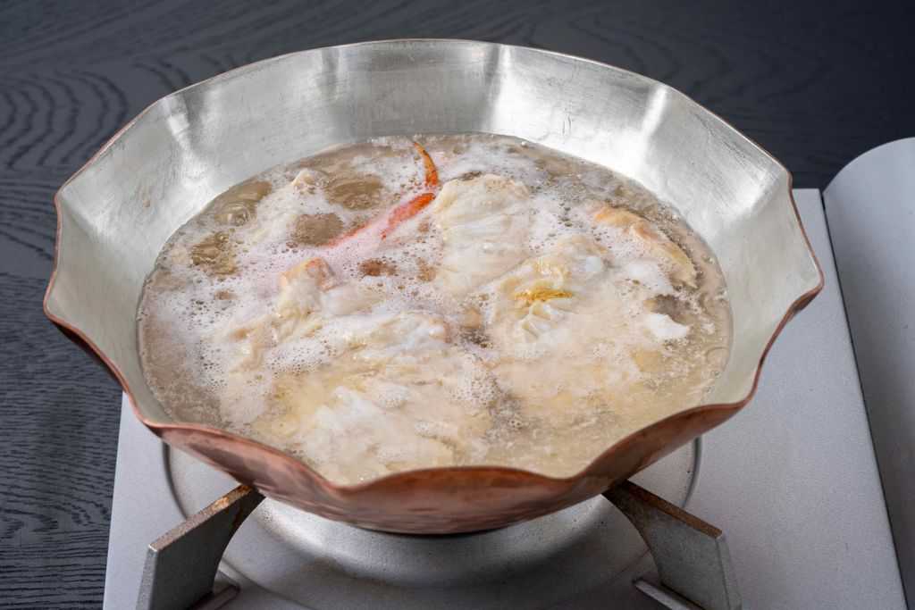 銅鍋の中で沸騰するズワイ蟹の肩肉が入ったスープ