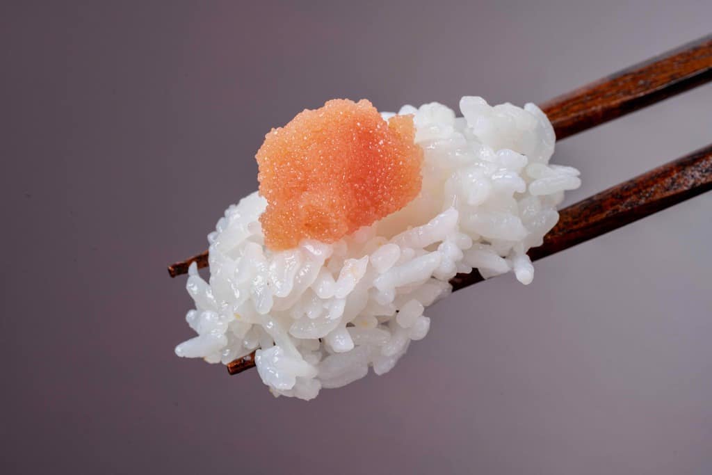 白飯と博多辛子明太子を箸でつまむ、ご飯の上の北海道噴火湾産できたて辛子明太子